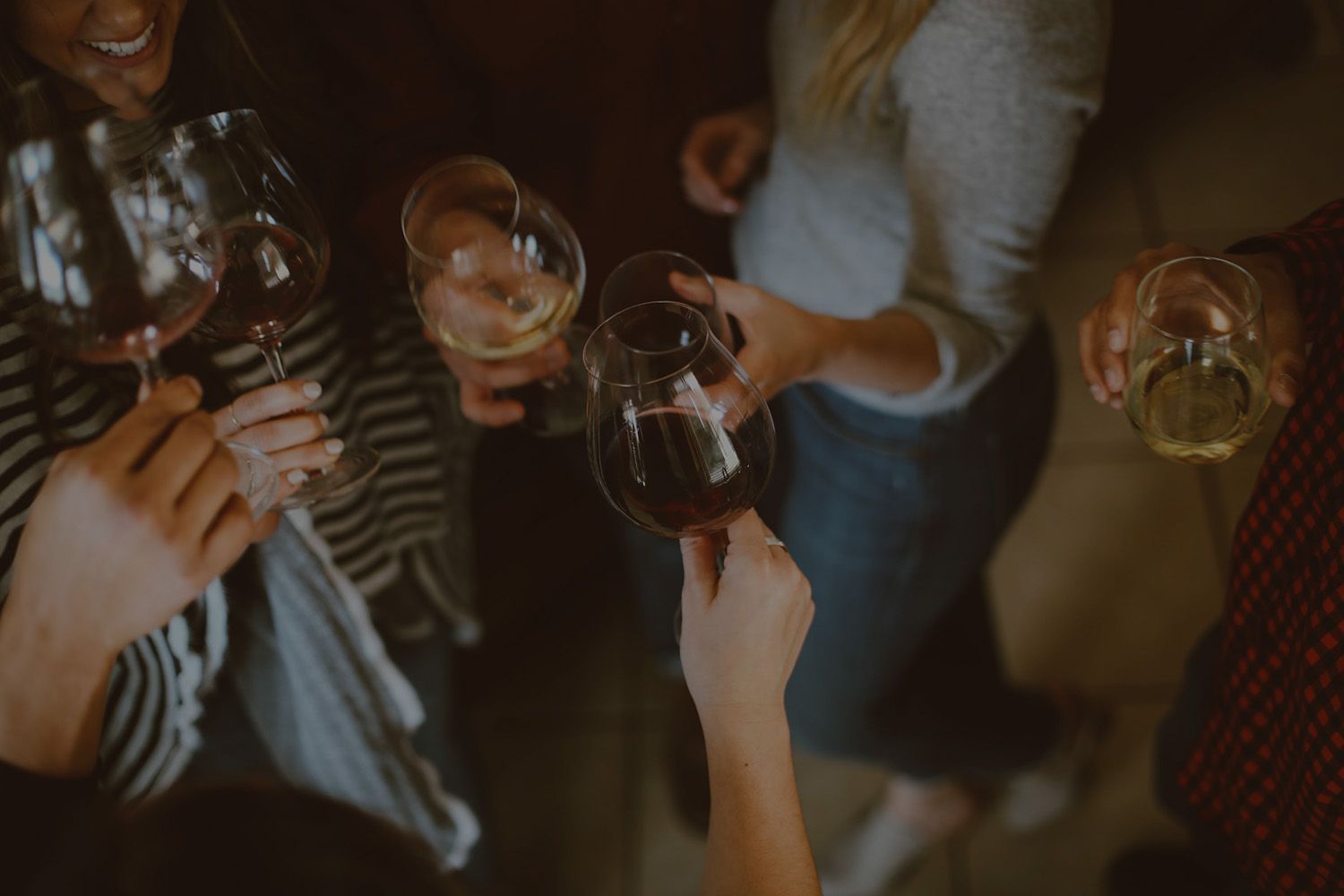 Detalle de copas de vino con personas brindando - filtro oscuro